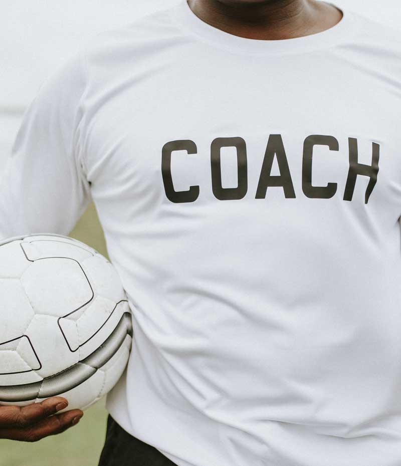 Ein Fußballtrainer, der in einem Stadion einen Ball hält